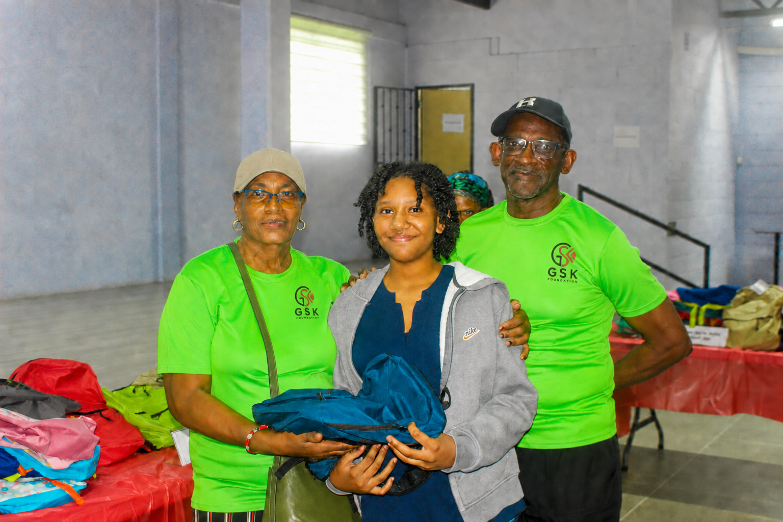 GSK Foundation volunteers standing with a student receiving school supplies
