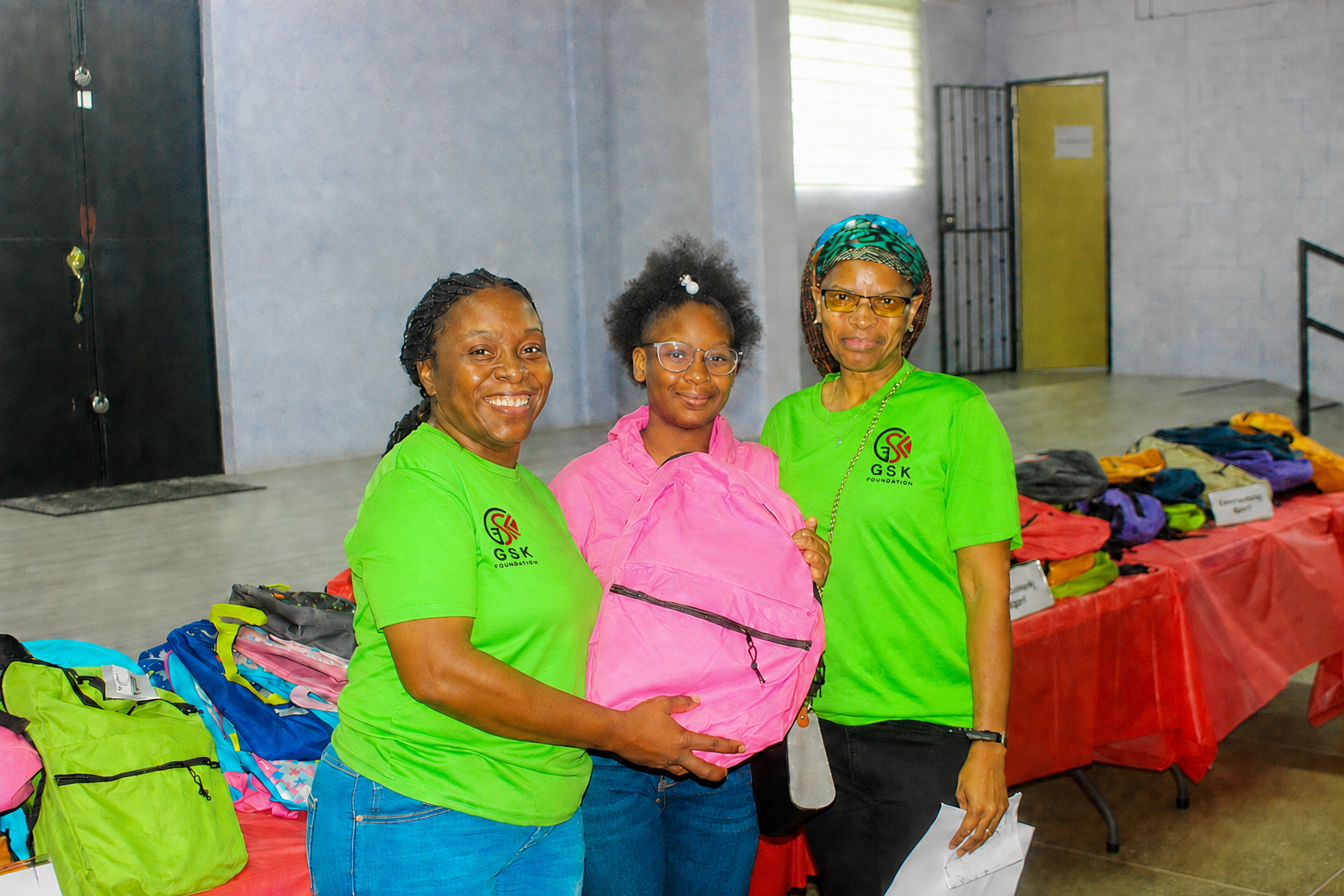 A student receiving a backpack with GSK Foundation volunteers