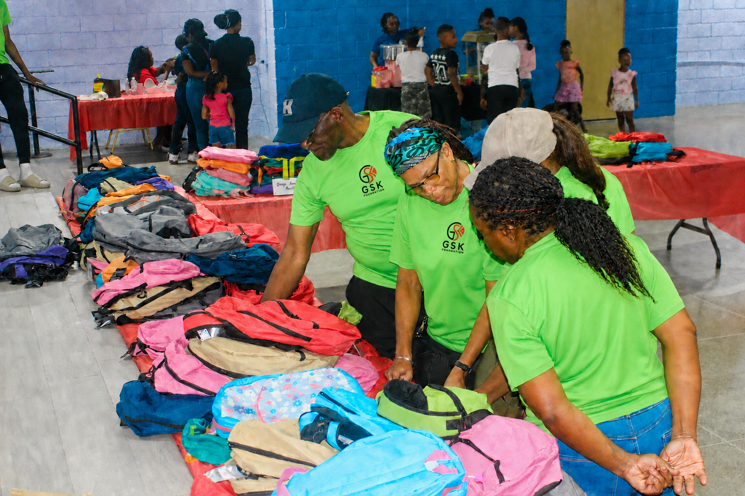 GSK Foundation volunteers organizing backpacks and school supplies at a Trinidad support event